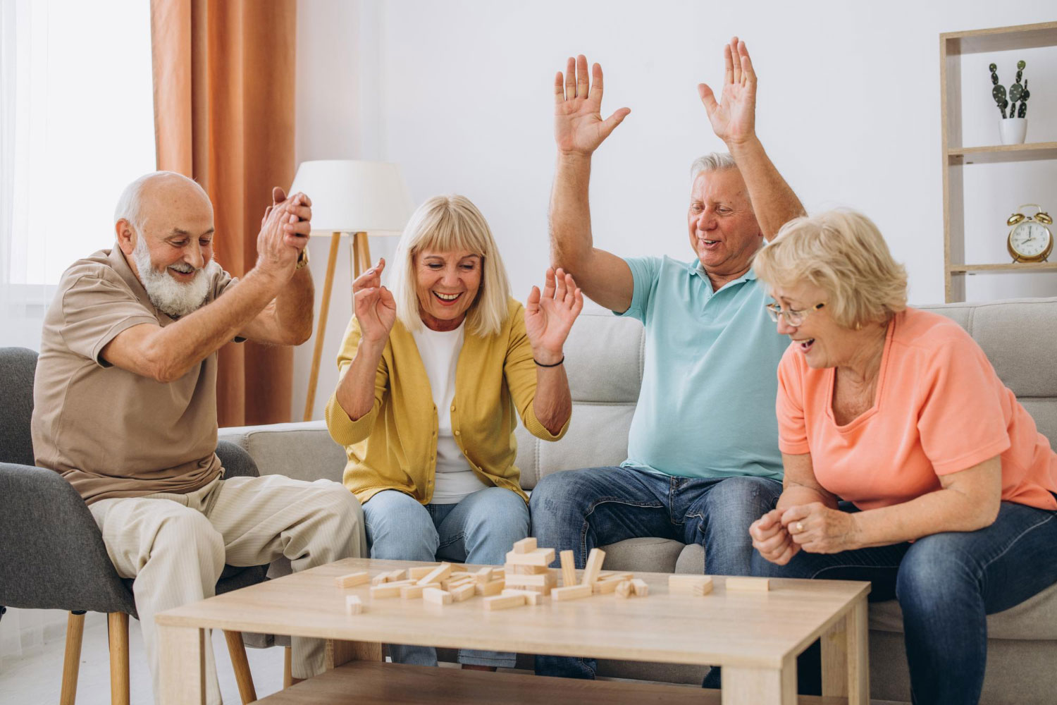Group of elderly friends joyfully playing Jenga at a table.