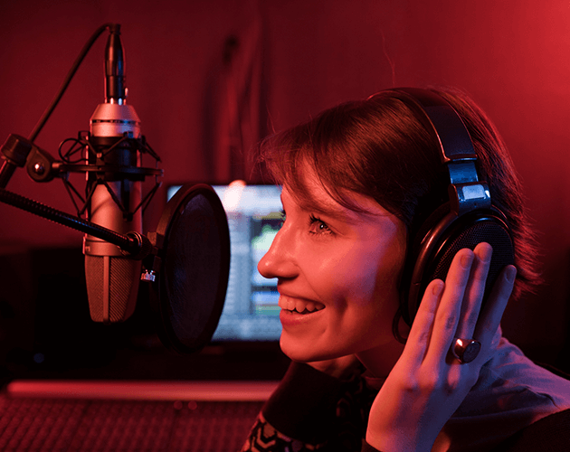 Young woman smiling while recording in a professional podcast studio.