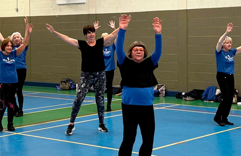 Seniors exercising energetically with arms raised in a group fitness class.